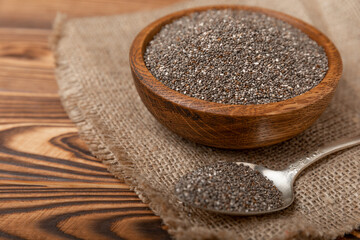 Chia seeds in bowl and spoons on brown wood texture. Diet food. Superfood. Healthy food. Space for text, copy space