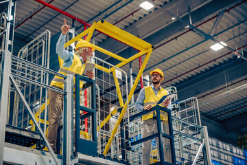 Two business people standing in warehouse and comparing data
