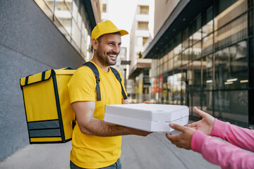 Young man in uniform as a courier delivering pizza - obrazy, fototapety, plakaty