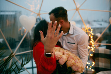 Young man and his happy fiancee showing engagement ring