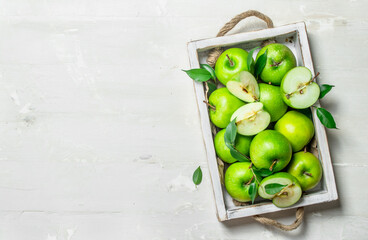 Green apples in a wooden tray.