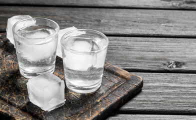 Vodka in a shot glass of ice on the cutting Board.