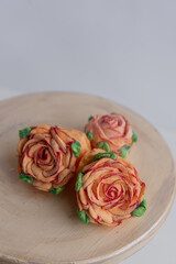 Obraz na płótnie Canvas On a wooden round background lie natural orange marshmallows in the form of roses flowers. Sweet desserts without sugar. Creative baking confectioners. Copy space, mock up. Sweet food