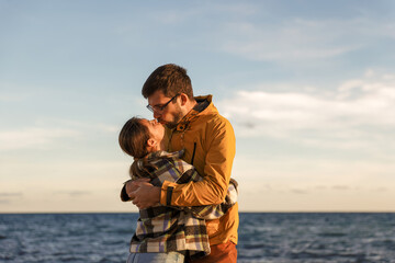 Happy couple hugging on the seashore at sunset of the day. Walk near the sea. Romantic time. Happy young people. Valentines day