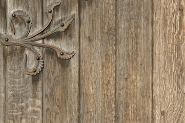 Fragment of an old wooden door with a metal decorative hinge.