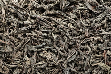 Close-up macro shot of the dry black tea leaves lying on a flat surface.
