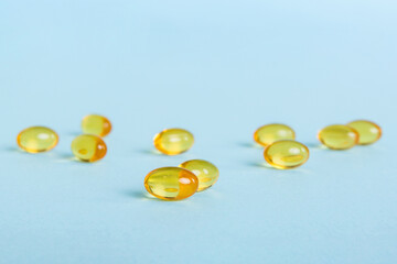 Heap of yellov pills on colored background. Tablets scattered on a table. Pile of red soft gelatin capsule. Vitamins and dietary supplements concept