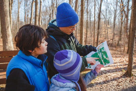 A father and children stand in forest in winter looking at map