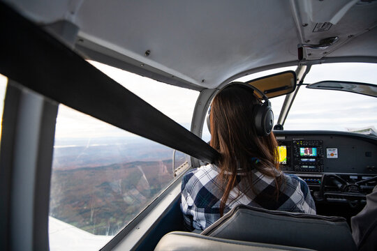 Young BIPOC Female Pilot flying a small airplane at sunrise