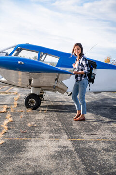 Young BIPOC Female Pilot doing preflight check on small plane