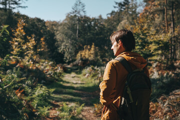 Young man traveler with backpack walks in sunny forest. Forest paths. Travel and active lifestyle.