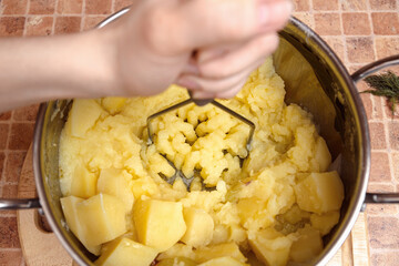 Woman preparing mashed potatoes with stainless potato masher. Cooking process, of mashed potato.