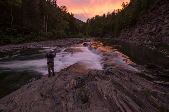 Fly fisherman casting into Le Chutes pool on York River at sunset, Gaspe, Quebec, Canada