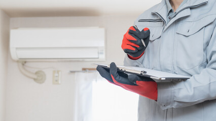 エアコンの掃除・点検をする作業服の男性