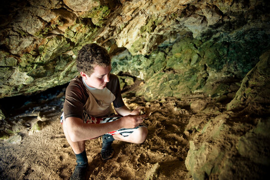 A young man looks at chert deposits in a cave on Santa Cruz Island off Santa Barbara CA.
