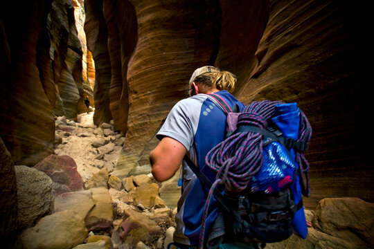 A man walks through a narrow wash in Zion National Park, Utah.