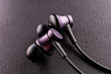 A symbol of the modern youth culture, sport, and technology, an image of a pair of earbuds on black background highlights the role of music in enhancing performance and style - 561145429