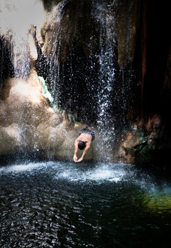Man dives through a waterfall at Finca Paraiso, Guatemala