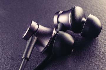 A representation of the youth culture, sport and modern technology, as a pair of earbuds on a black background symbolize the use of technology to enhance performance and style - 561145621