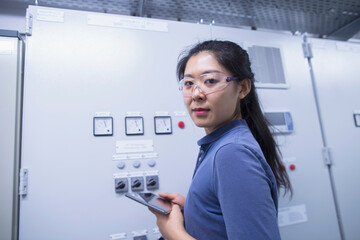Young female engineer updating control panel using digital tablet in an industrial plant, Freiburg im Breisgau, Baden-Württemberg, Germany