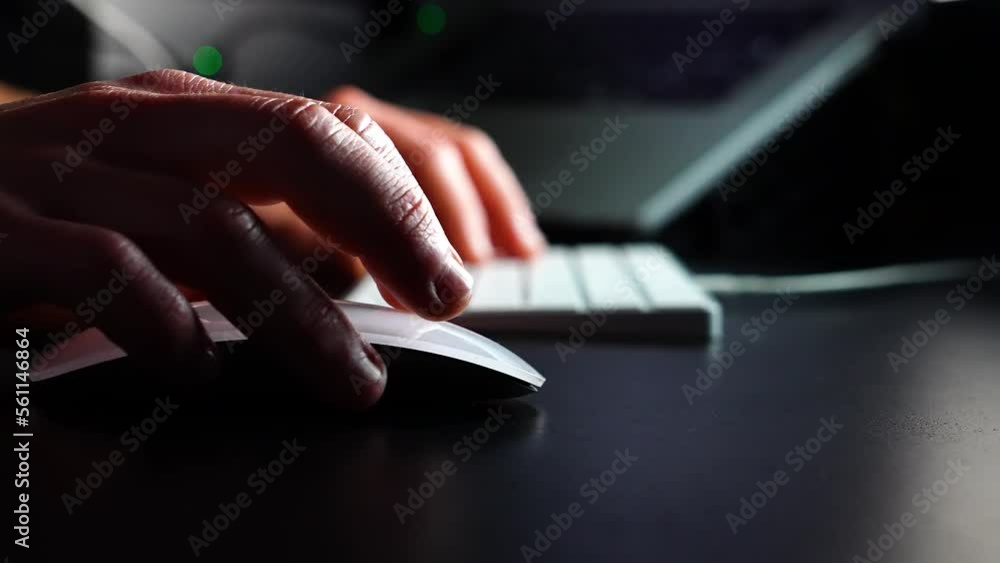 Poster person using a mouse in dark room, typing on keyboard on computer - slow-motion shallow depth of fie
