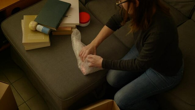 Female packing collectable retro rocket preparing various items for home moving