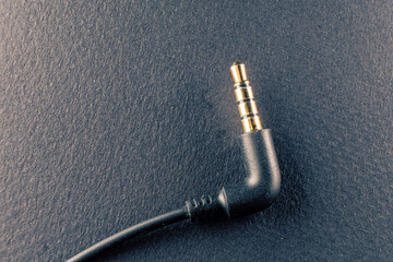 A representation of the audio technology and art, a golden plated 3.5mm jack on a black background symbolizes the connection between sound and design - 561147064