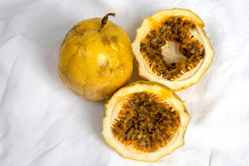 Passion fruit, whole and sliced, on white tablecloth background