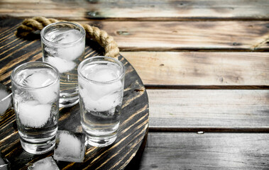 Vodka in a shot glass and ice cubes on tray.