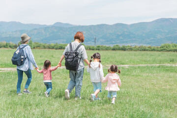 Obraz premium ママ友家族を公園を歩く親子の後ろ姿（女友達・母子家庭）