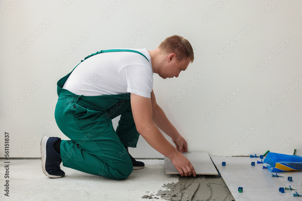 Wall mural Worker installing ceramic tile on floor near wall