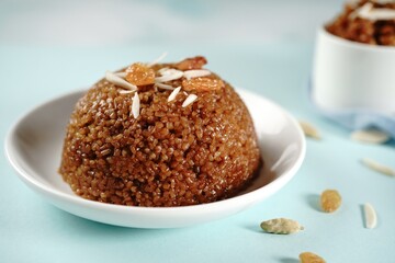 Obraz na płótnie Canvas Homemade broken wheat sweet chakarai pongal topped with nuts and raisins, selective focus