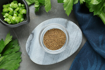 Bowl of celery seeds and fresh plant on grey table, flat lay