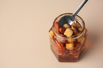 Jar with different nuts and honey on light table, space for text