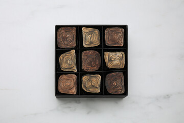 Box of tasty chocolate candies on white marble table, top view