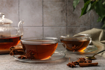 Aromatic tea with anise stars and cinnamon sticks on light grey table. Space for text