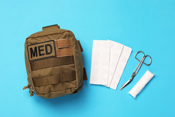Military first aid kit on light blue background, flat lay