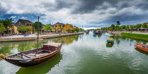 Fototapeta na wymiar Boats on a river in front of an historic township with dark clouds overhead