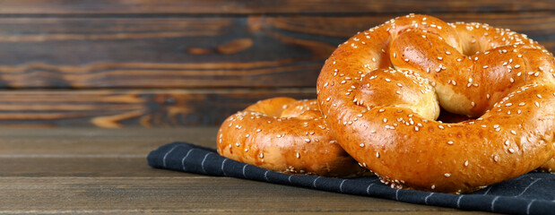 Tasty freshly baked pretzels on wooden table, space for text. Banner design