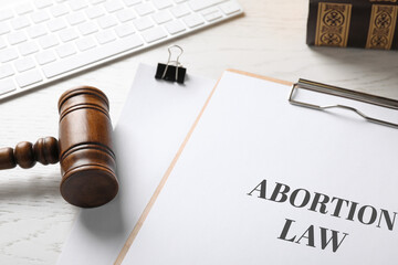 Clipboard with text Abortion Law and gavel on white wooden table, closeup