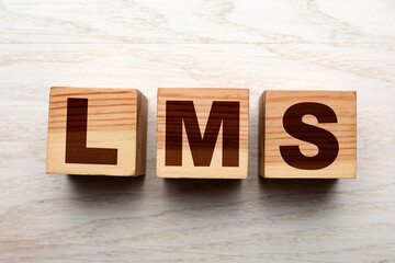 Learning management system. Cubes with abbreviation LMS on wooden background, top view