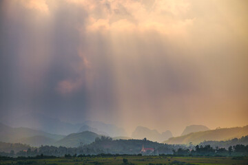 Fototapeta na wymiar Dramatic rays of light breaking through clouds over a mountainous landscape at Phong Nha in Vietnam