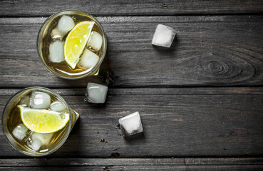 Whisky in glasses with ice and lime slices.