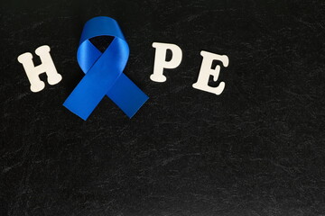 Dark blue ribbon color isolated on dark black background. Colon and colorectal cancer awareness and hope concept.