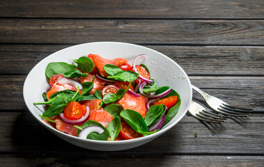 Fish salad. Salad with slices of salmon, tomatoes and spinach with lime juice.