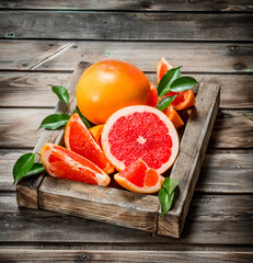 Ripe grapefruit on a wooden tray.