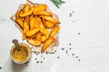 Baked potato wedges with mustard and a sprig of rosemary.