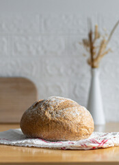 One white round bread with wheat fiber on the table.