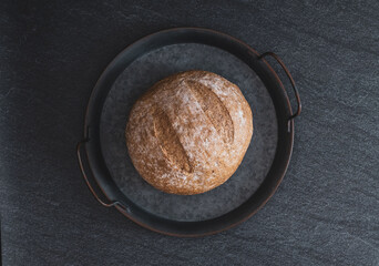 One rye round bread on a black background.