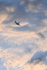 Silueta de avion volando con el cielo al atardecer con nubes coloridas